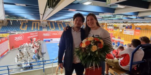 Ehrung Berni: Berni posiert mit Blumenstrauß neben Hitoshi im Zuschauerraum der Halle