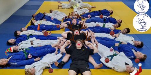 Ein Weihnachtsbaum geformt aus Judo-Kindern, die am Boden liegen